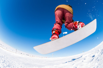 Snowboarder jumping against blue sky