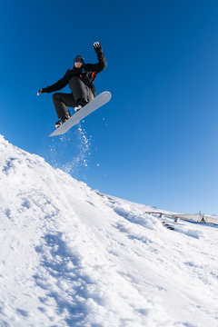 Snowboarder jumping against blue sky