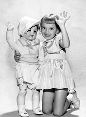 Portrait of a girl kneeling and holding her lifesize doll 