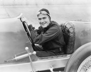 Young man sitting in a race car with a big smile 