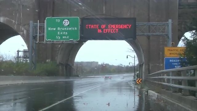 Waves whip the shore and roads show emergency signs during Hurricane Sandy.
