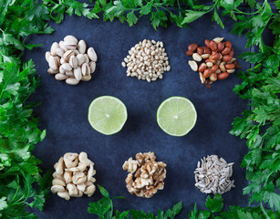 Pistachios, pine nuts, peanuts, cashews, walnuts, lime, and sesame seeds with parsley on grunge background. Flat lay.