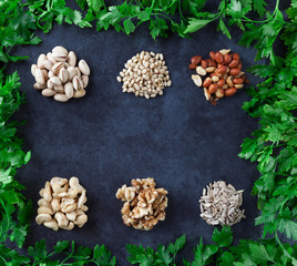 Pistachios, pine nuts, peanuts, cashews, walnuts, and sesame seeds with parsley on grunge background. Flat lay.