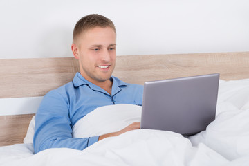 Man Using Laptop On Bed