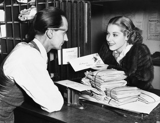 Clerk with woman mailing letter 