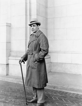 Elegantly Dressed Man Standing In Front Of A Building 