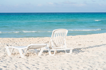 White plastic chairs on white sand beach