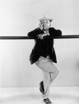 Man leaning against a balance beam with his legs crossed 