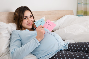 Pregnant Woman Holding Paper With Girl And Boy Written On It
