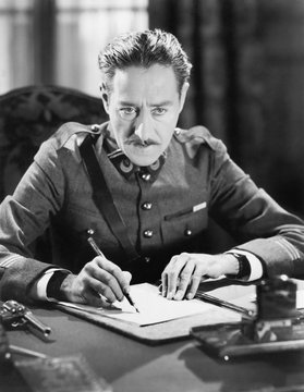 A Soldier Writing A Letter With A Gun Next To Him 