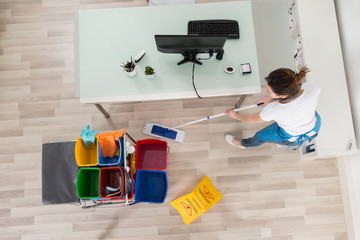 Young Female Janitor Mopping Wooden Floor