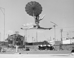 Female acrobat doing splits on tightrope 