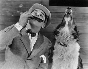 Man playing harmonica with howling dog 