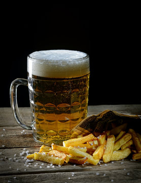 fried french fries and beer on a wooden background