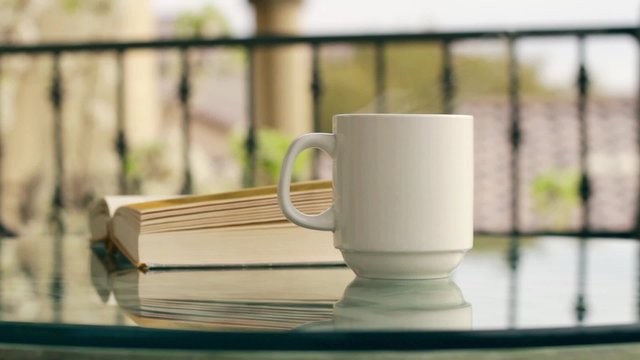 Hot coffee steaming on cafe table with book
