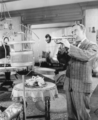 Man standing in his living room playing the trumpet to a bird 