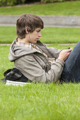 College student listening to digital music audio device on university campus