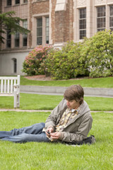 College student listening to digital music audio device on university campus