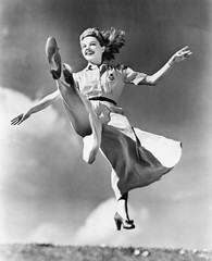Kobieta w przepływającej sukience skaczącej w powietrzu - 104450148