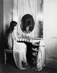 Woman looking in mirror at dressing table 