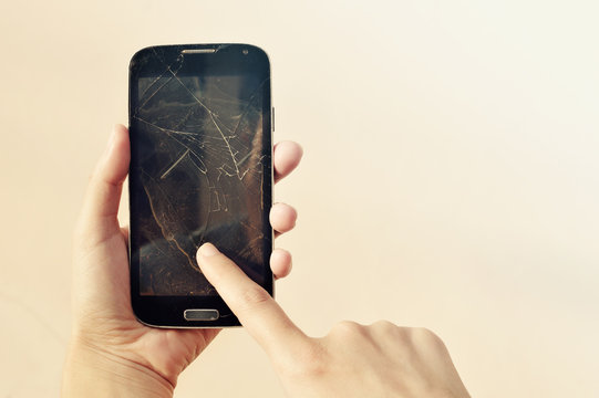 Woman hand holding a smartphone with cracked screen