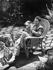 Man sitting in chair outside with dog 