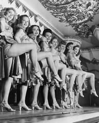 Chorus line of women with legs lifted 