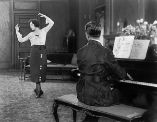Kobieta tańczy, podczas gdy jej mąż gra na pianinie - 104453174