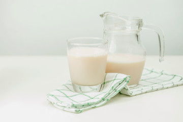 Milk in a glass jug and glass on wooden background