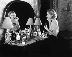 Young woman in front of her vanity applying makeup  - 104454567