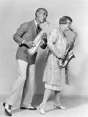 Couple playing saxophones together 