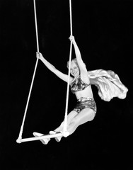 Portrait of a female circus performer performing on a trapeze bar  - 104455569