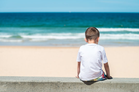 Sad boy sitting at the beach