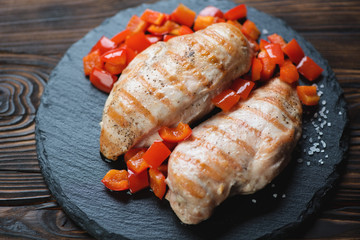 Stone slate with grilled chicken breast filet, studio shot