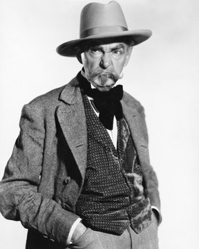 Man in a hat and vest looking grumpy 