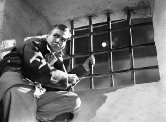 Fototapeta premium Low angle view of a young man trying to escape from a prison cell 