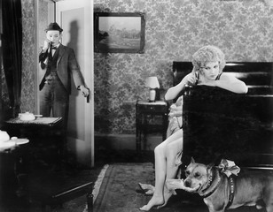 Man standing in the doorway looking at a woman angry at her dog 