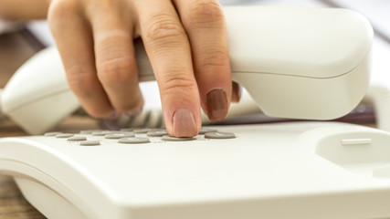 Closeup of female hand dialing telephone number - obrazy, fototapety, plakaty