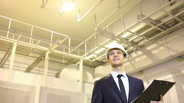 man in business suit and helmet. inspects premises. consults with the plan. pleased with the good work