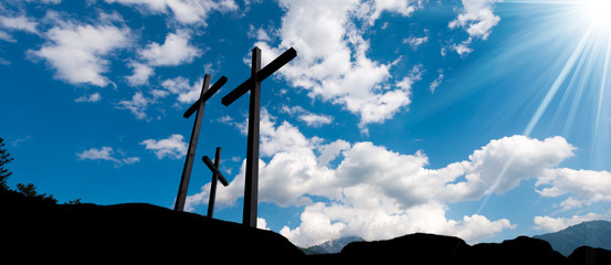 Crosses Silhouette against Blue Sky / Silhouette of three crosses against a blue sky with clouds and sun rays. Carisolo Trentino Italy