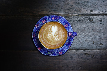 cup of latte art coffee on wooden background