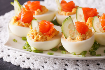 Delicious eggs stuffed with salmon, cheese and cucumber closeup 
