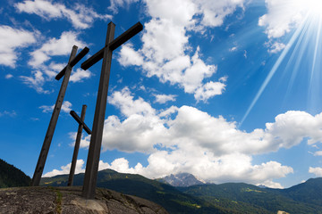Crosses Silhouette against Blue Sky / Silhouette of three crosses against a blue sky with clouds and sun rays in mountain. Brenta Dolomites, Trentino, Italy