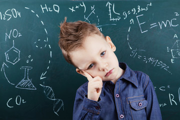 Little boy near blackboard with formulas