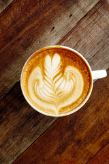 cup of latte art coffee on wooden background