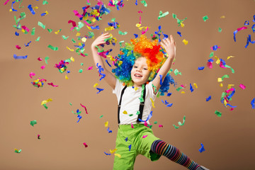 Little boy in clown wig jumping and having fun celebrating birth