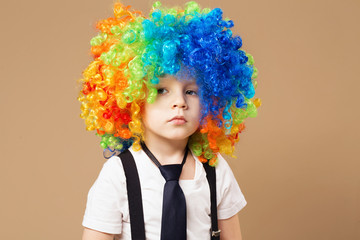 Sad clown boy with large colorful wig.