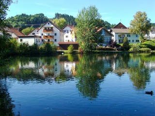 Fototapeta na wymiar Houses laid against a pond in Peiting, Germany