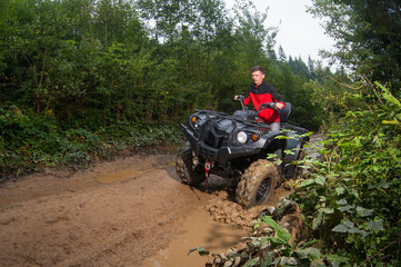 Man driving four-wheeler ATV through mud