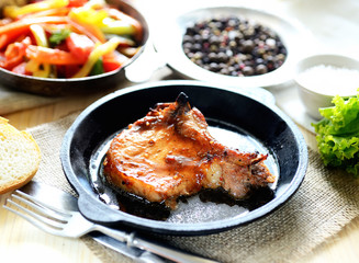 pork steak in a frying pan, fried vegetables